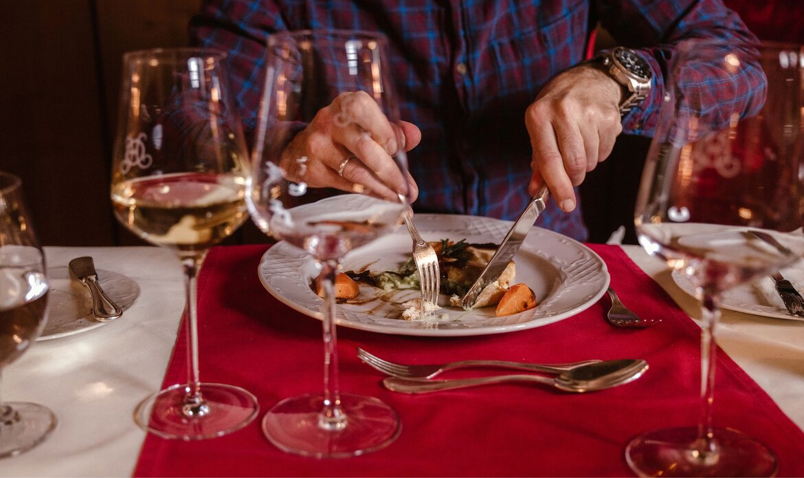 Eine Person isst am gedeckten Tisch ein Abendmenü mit mehreren Gängen im GRAND HOTEL Zell am See.