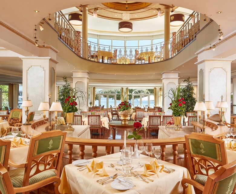 Ein elegantes Hotelrestaurant mit gedeckten Tischen, Blumenarrangements und Blick auf den See.
