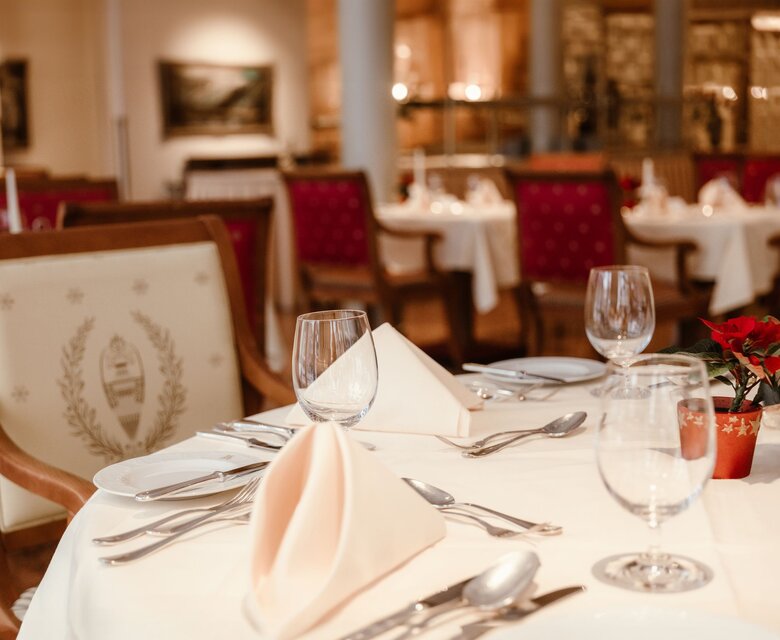 Ein festlich gedeckter Tisch im Hotelrestaurant mit Gläsern, Besteck und gefalteten Servietten.