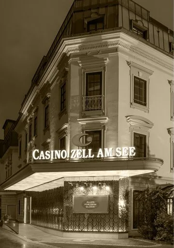 Das Eckgebäude des Grand Hotel Zell am See mit beleuchtetem Casino-Schriftzug bei Nacht.