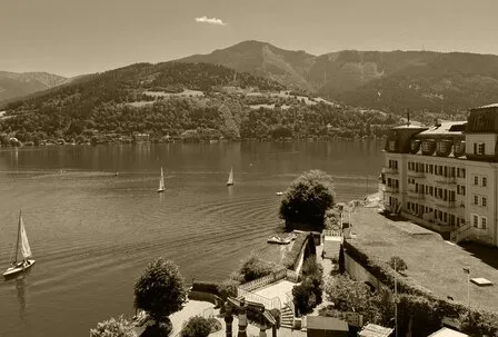 Der Blick zeigt das Grand Hotel am Ufer des Zeller Sees mit Segelbooten und Bergkulisse.