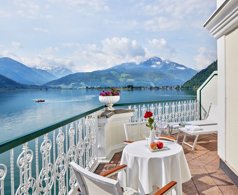 Ein Balkon mit Tisch, Stühlen und Blick auf den See sowie die Berge.