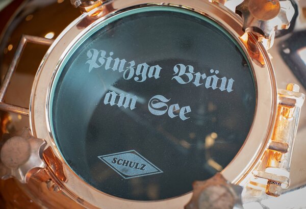 A brewing kettle lid shows the Pinzga Bräu am See lettering and the Schulz logo on the glass window.