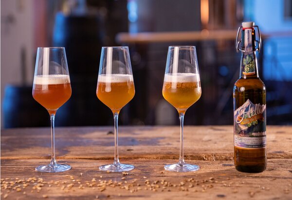 Drei Gläser Bier und eine Flasche auf einem Holztisch in der Hausbrauerei des Pinzga Bräu.