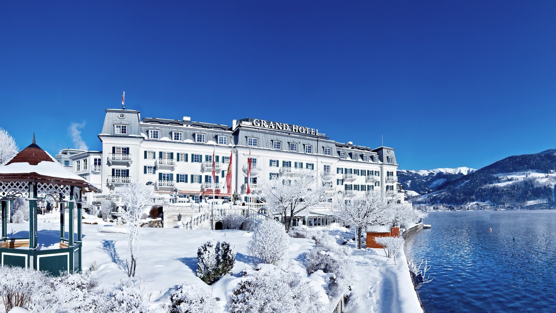 Das GRAND HOTEL Zell am See liegt verschneit direkt am Ufer des Zeller Sees.