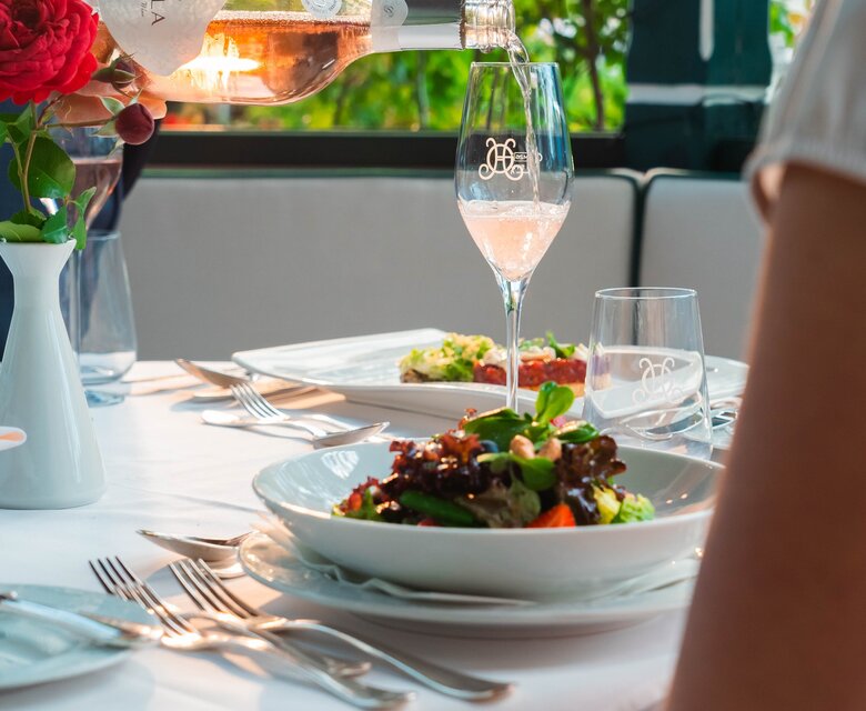 Ein Kellner schenkt Roséwein am gedeckten Tisch im Hotelrestaurant ein.