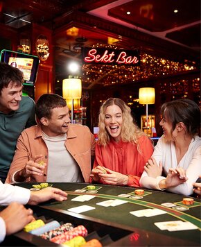 Junge Gäste sitzen an einem Spieltisch in der Sekt Bar des Casinos.