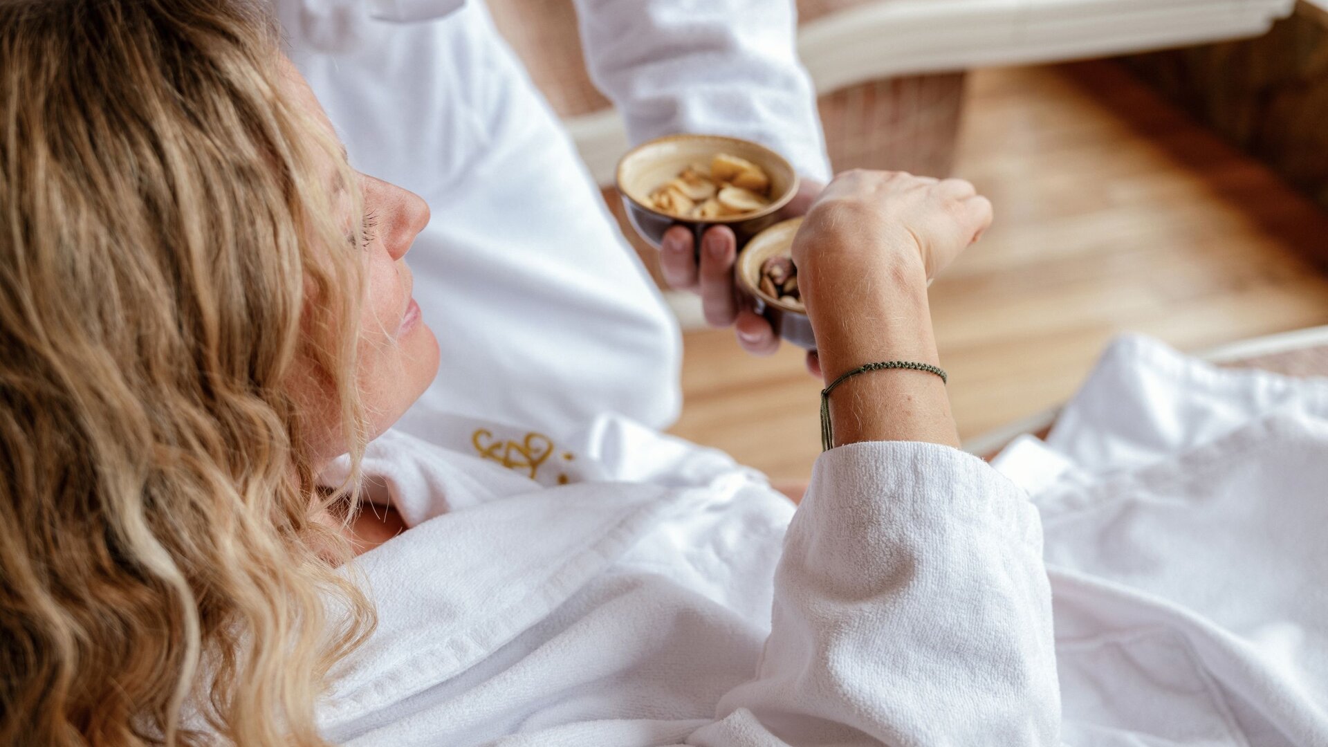 A woman receives a hand massage in the GRANDSPA while a therapist holds small bowls nearby.