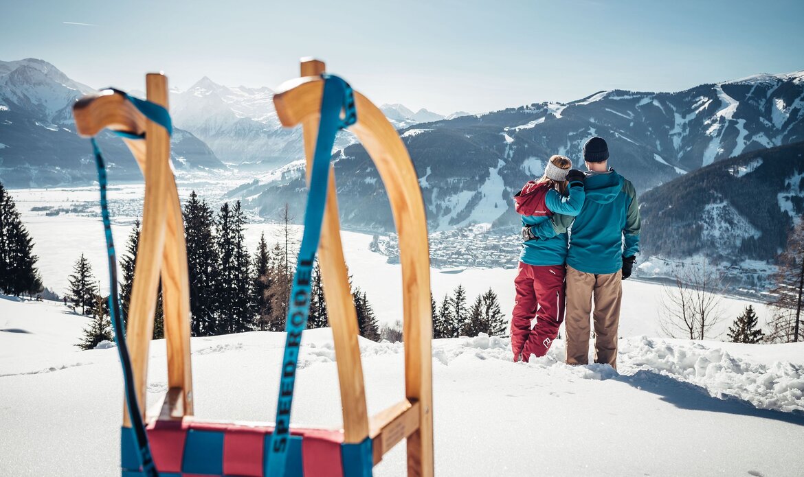 Ein Paar steht im Schnee und blickt über das winterliche Tal auf die Berge im Pinzgau.