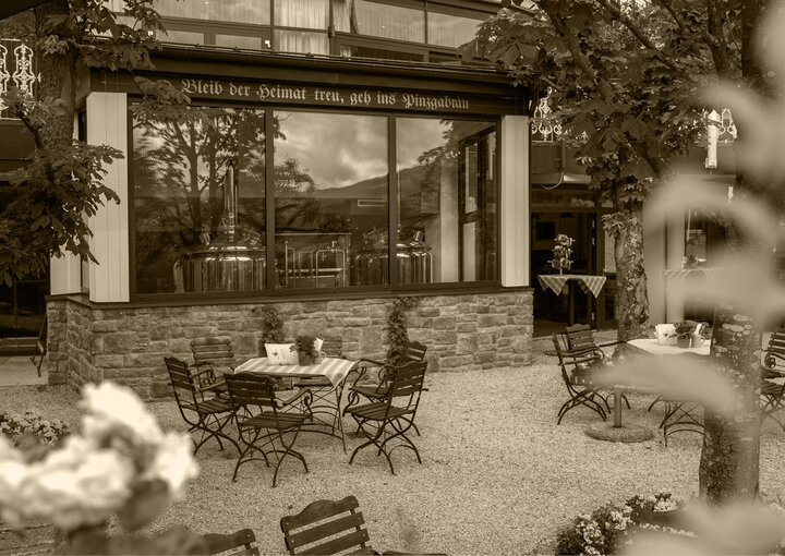 Eine historische Hotelterrasse mit Metalltischen und Stühlen vor dem Grand Hotel am Zeller See.