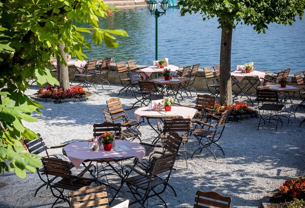 Der Gastgarten mit gedeckten Tischen liegt unter Bäumen direkt am Zeller See.