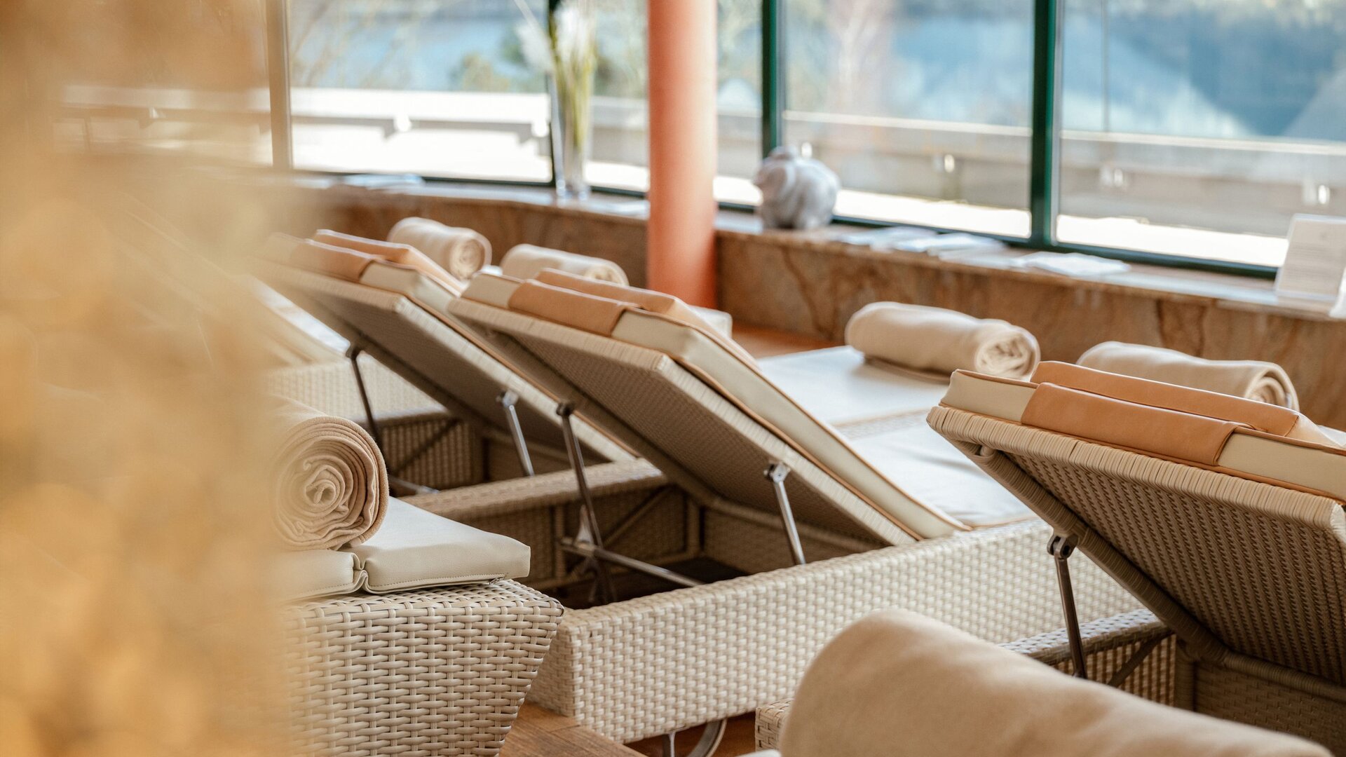 Ein Ruheraum mit Liegen und aufgerollten Handtüchern am Fenster im GRANDSPA des GRAND HOTEL Zell am See.