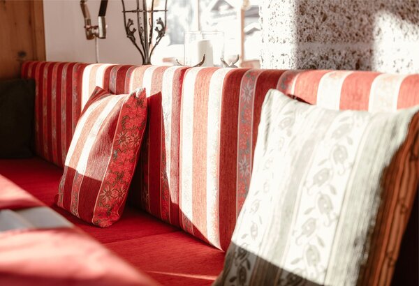 Eine rot-weiß gestreifte Sitzbank mit roten und weißen Kissen im hellen Hotelrestaurant.