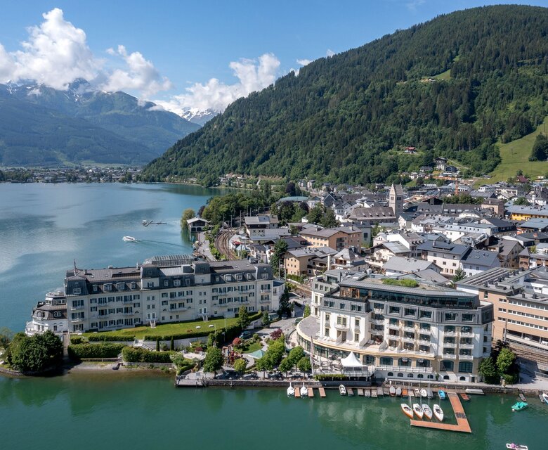 Blick über Zell am See mit dem Zeller See, dem Ufer und dem GRAND HOTEL am Wasser.