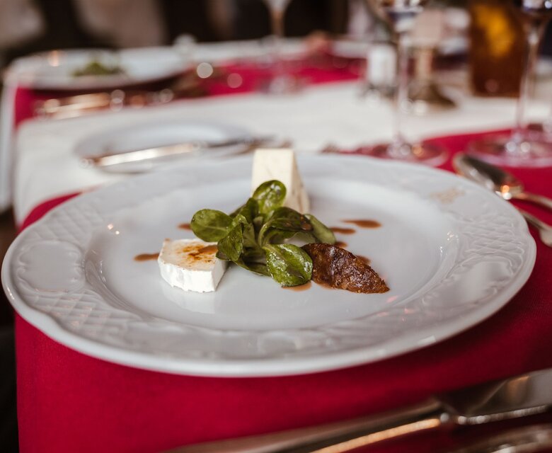 Auf einem weiß gedeckten Tisch steht ein Teller mit einem kleinen Dessert im Hotelrestaurant.