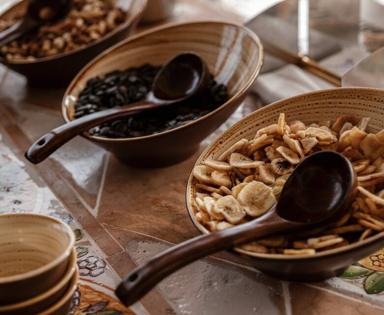 تقف عدة أوعية من الحبوب والفواكه المجففة على طاولة بوفيه مع ملاعق.