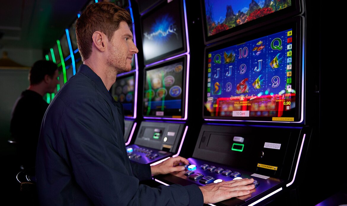 A man is playing at a lit slot machine in Casino Zell am See.