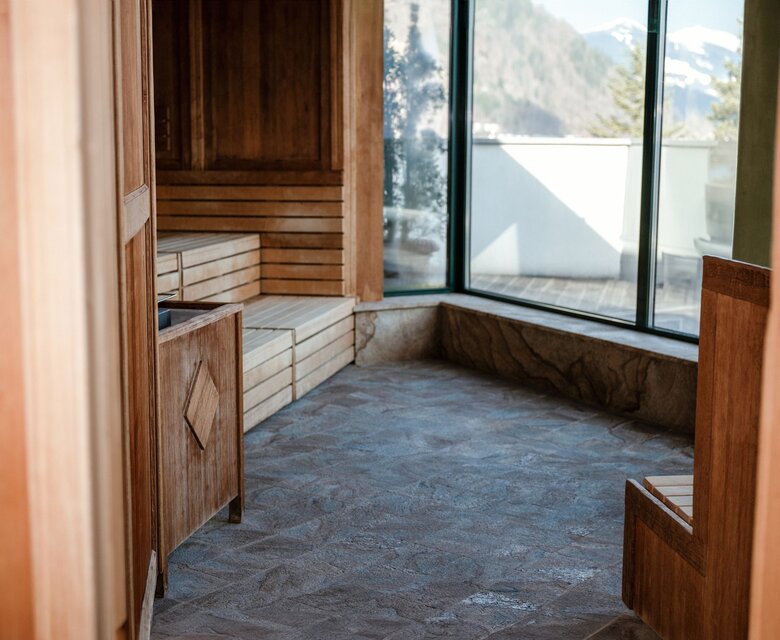 Eine Holzsauna mit Fenster und Blick auf die Berge.