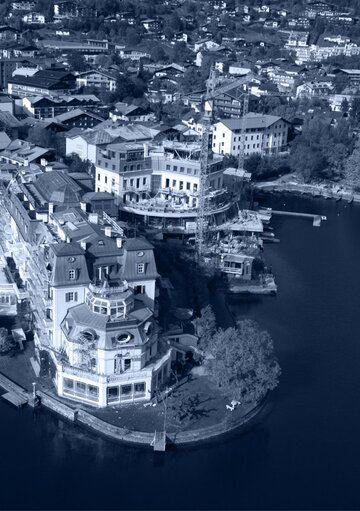 Luftaufnahme eines historischen Hotelgebäudes an der Uferlinie des Zeller Sees in Zell am See.