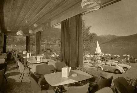 Ein historisches Hotelrestaurant mit großen Fenstern blickt auf den Zeller See und die umliegenden Berge.