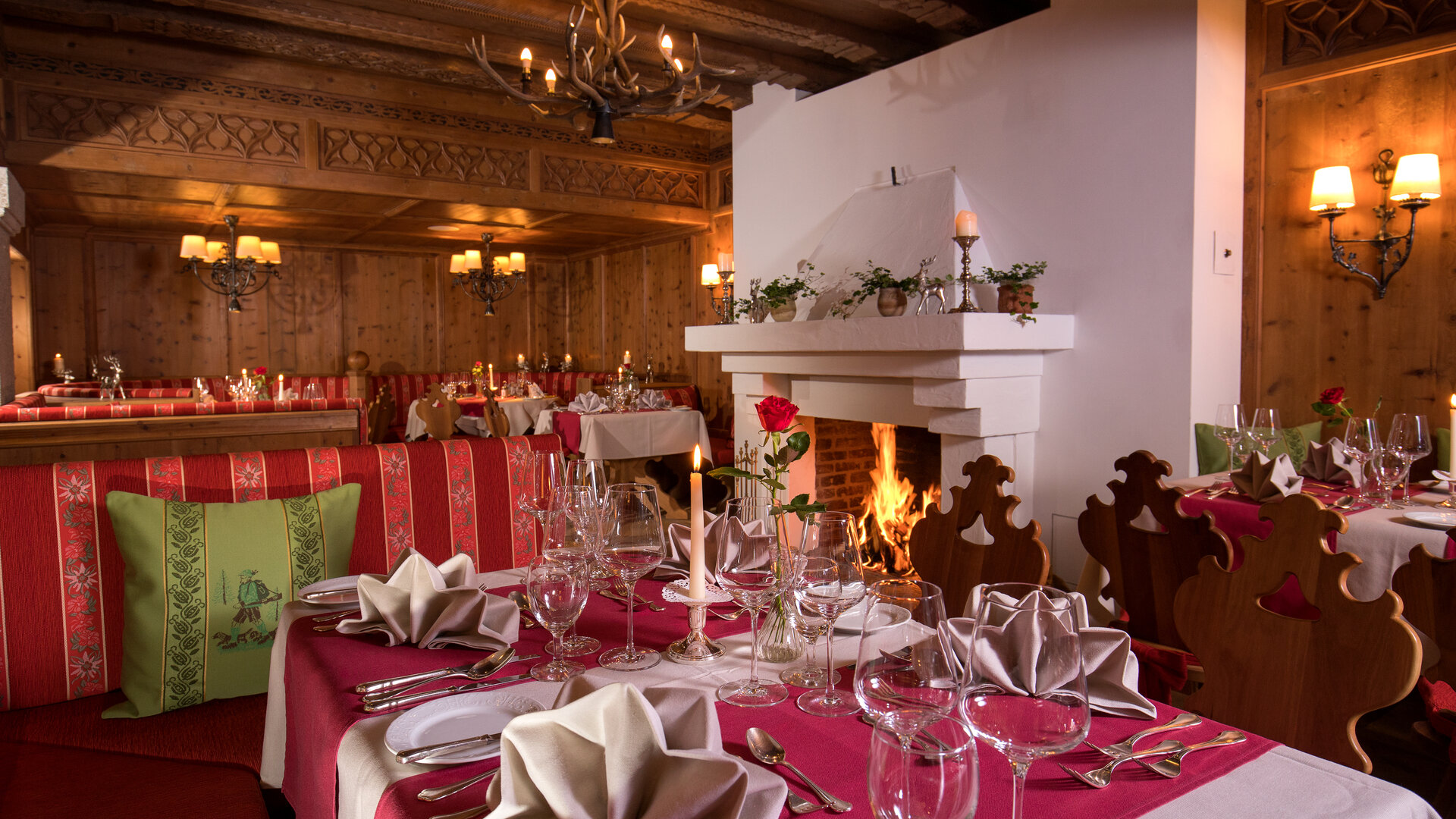 Ein stilvoll gedeckter Tisch im Restaurant mit Kamin und Holzdecke im GRAND HOTEL Zell am See.