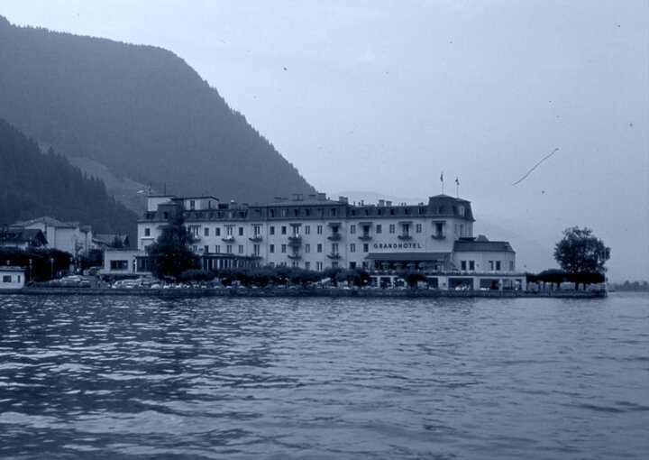 Das GRAND HOTEL Zell am See liegt am Ufer des Sees vor einer Bergkulisse.