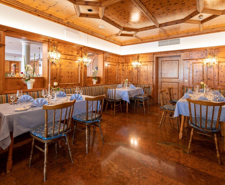 Ein holzvertäfelter Speisesaal mit eingedeckten Tischen im GRAND HOTEL Zell am See.