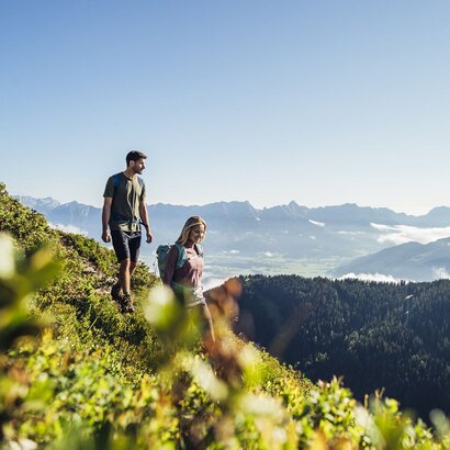 Ein Wanderpaar steht auf einem Bergpfad mit Blick über die Alpen und den See bei Zell am See.