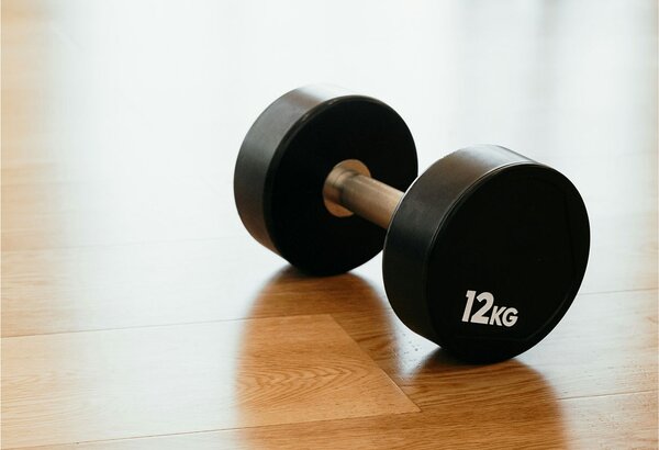 Eine 12-kg-Hantel liegt auf dem hellen Holzboden im Fitnessbereich des GRANDSPA.