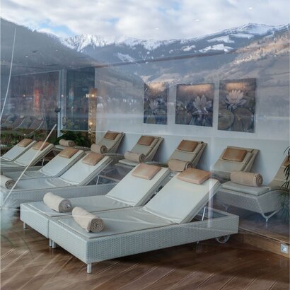 Liegestühle und Ruhebetten im Ruheraum des Adults Only GRANDSPA mit Bergblick durch die Glasfront.