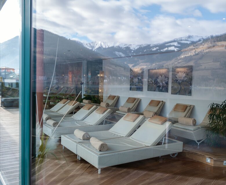 Im Ruheraum stehen mehrere Liegen vor der Glasfront mit Blick auf die Berge.